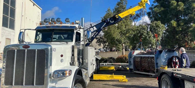 Armada Towing Kyle TX rotator lifting heavy machinery onto flatbed