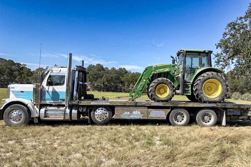 Armada Towing Service equipment transport truck carrying John Deere tractor