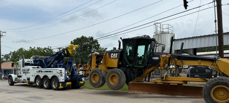Heavy-duty rotator lifting CAT motor grader at Kyle TX job site