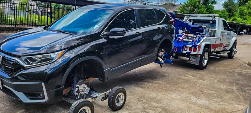 Wheel-lift tow truck towing black crossover SUV in Bastrop TX