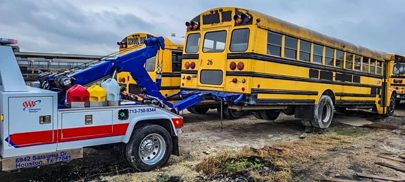 Heavy-duty tow truck preparing to tow a school bus in Lockhart