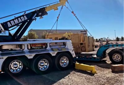 Armada Towing Service rotator lifting industrial equipment beside lowboy trailer
