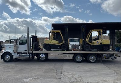 Armada Towing Service equipment transport carrying two warehouse forklifts