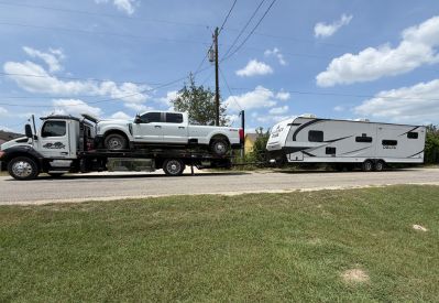 Armada Towing Service rollback with pickup beside travel trailer